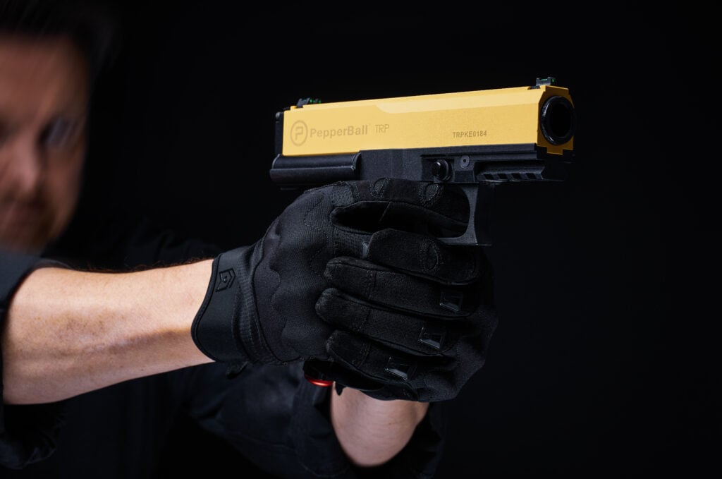 Officer holding a PepperBall non-lethal launcher ready for tactical deployment