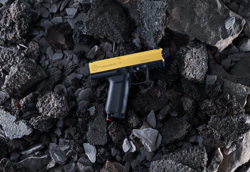 PepperBall non-lethal launcher placed on rough terrain during tactical deployment